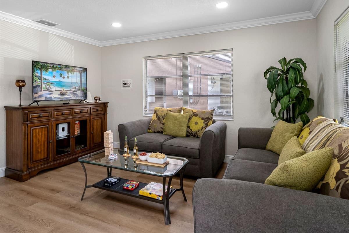 At the center of the room are two plush, soft grey couches, perfectly positioned to encourage relaxation, conversation, or a laid-back movie night.