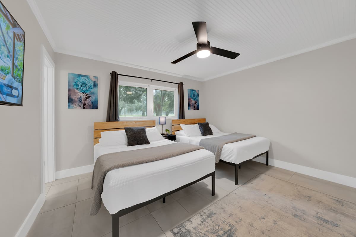 Coastal art on the walls, two identical beds, a window letting the green outside in, a kids' room that doesn't feel like an afterthought.