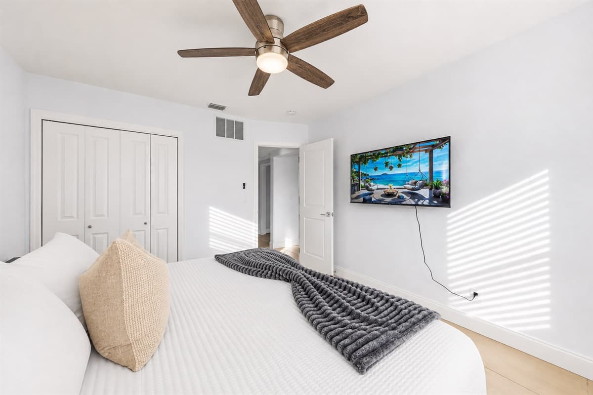 Bright guest bedroom featuring plush bedding, TV, and clean contemporary styling.