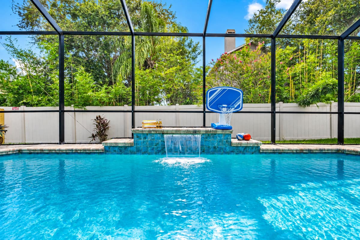 Enjoy the outdoors without the bugs! This screened-in pool area features serene water features, sports games, and ample space to swim or unwind.