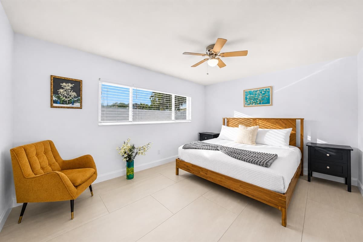 Elegant bedroom setup with comfortable bedding, accent seating, and large windows.