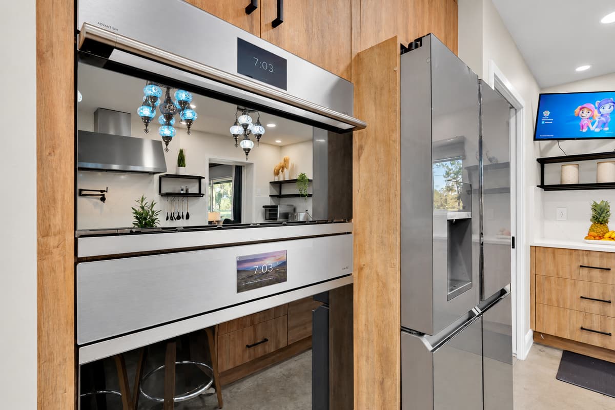 Double ovens, so nothing waits its turn. Full-size wall ovens beside a large refrigerator, with prep space in between — Thanksgiving-scale cooking without a single compromise.
