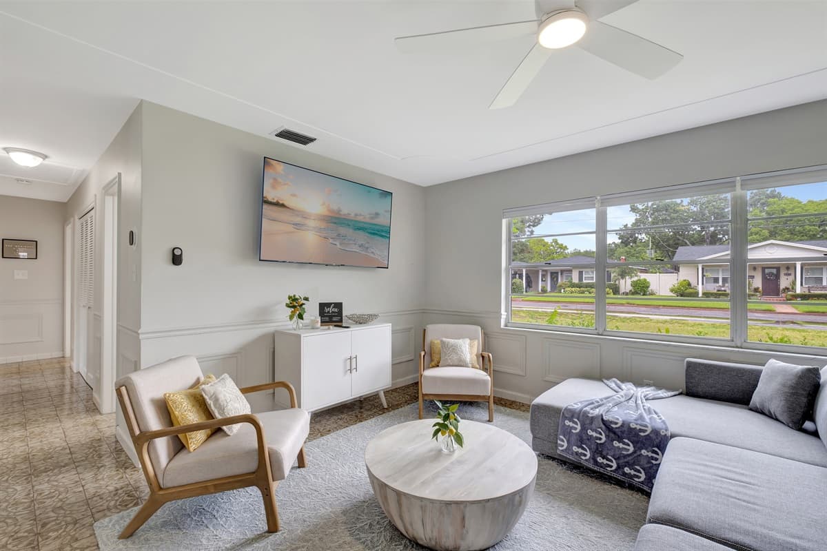 As you lounge on the couch, your gaze is drawn to a massive window that spans an entire wall, allowing an abundance of natural light to flood the room.
