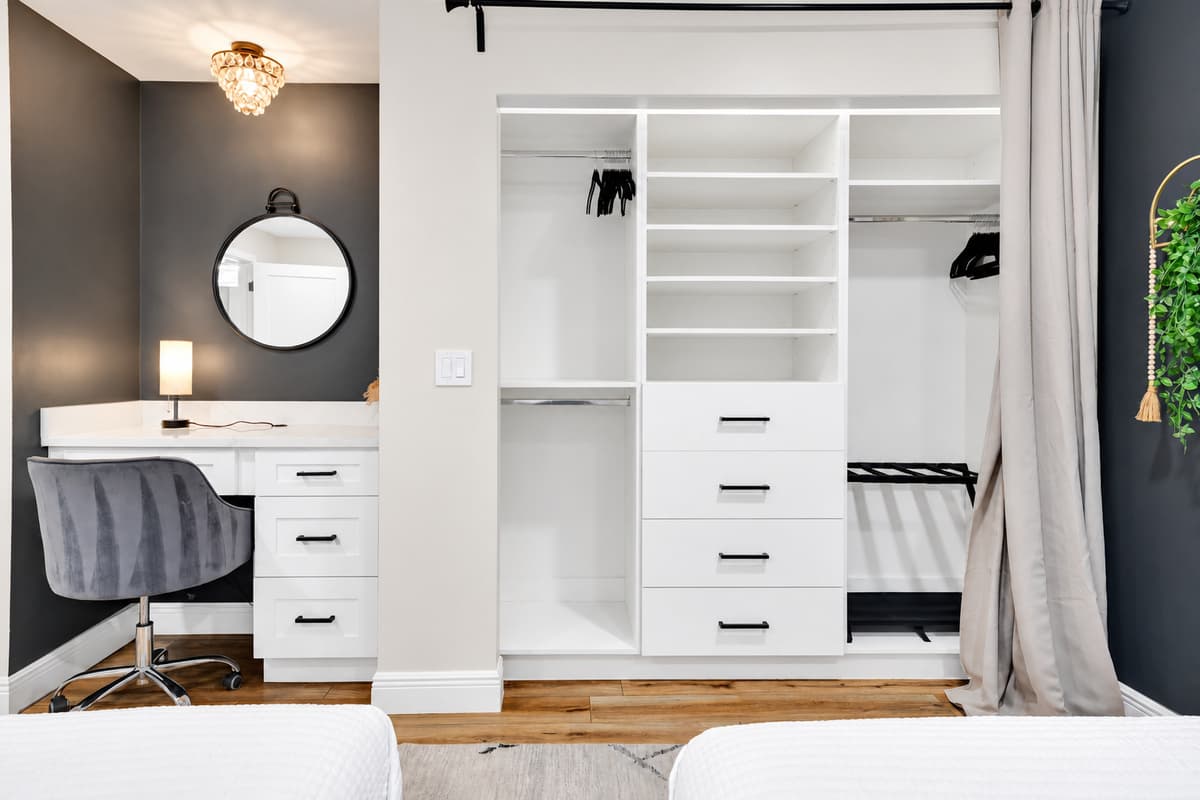 Dressing room, vanity and closet, all yours. Lit mirror, wide counter, drawers and full hanging space beside the bed — the room for whoever in the group takes the longest to get ready.