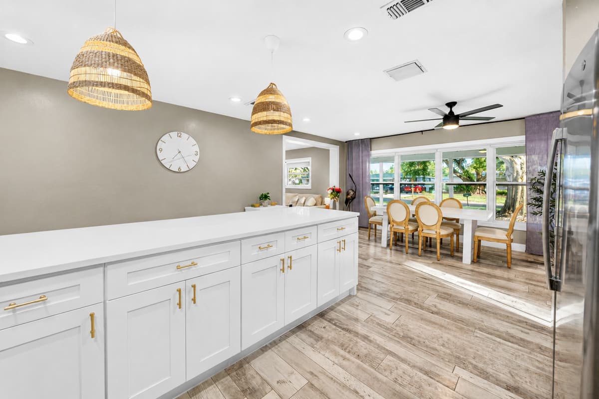 Contemporary chef's kitchen featuring white shaker cabinets, stainless steel appliances, patterned tile backsplash, and spacious countertops.