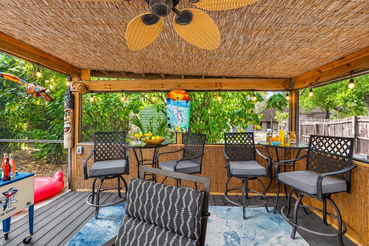This colorful patio is packed with personality—featuring playful tiki carvings, island-themed décor, a bar setup, and cozy seating.