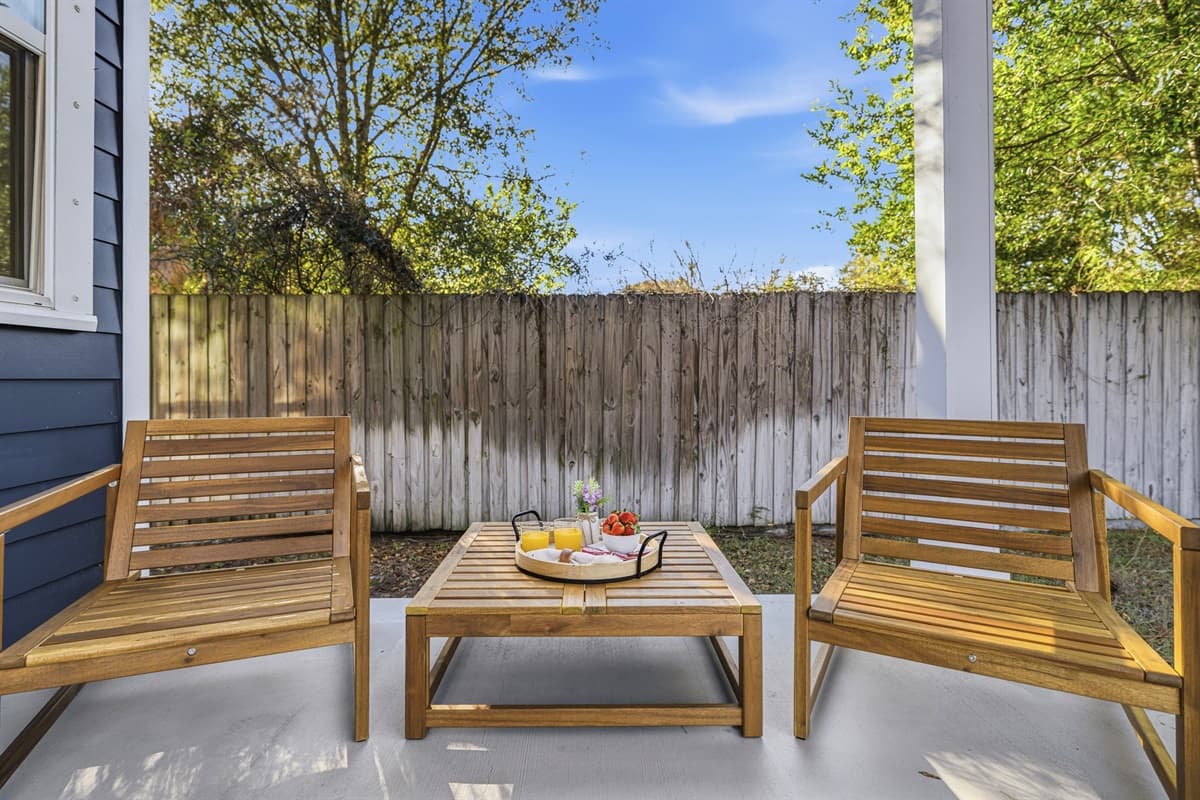 Unwind in style — the backyard sitting area features gorgeous teak lounge chairs, a coffee table with snacks, and a wood privacy fence. The ultimate outdoor escape right here in Seminole Heights, Tampa.