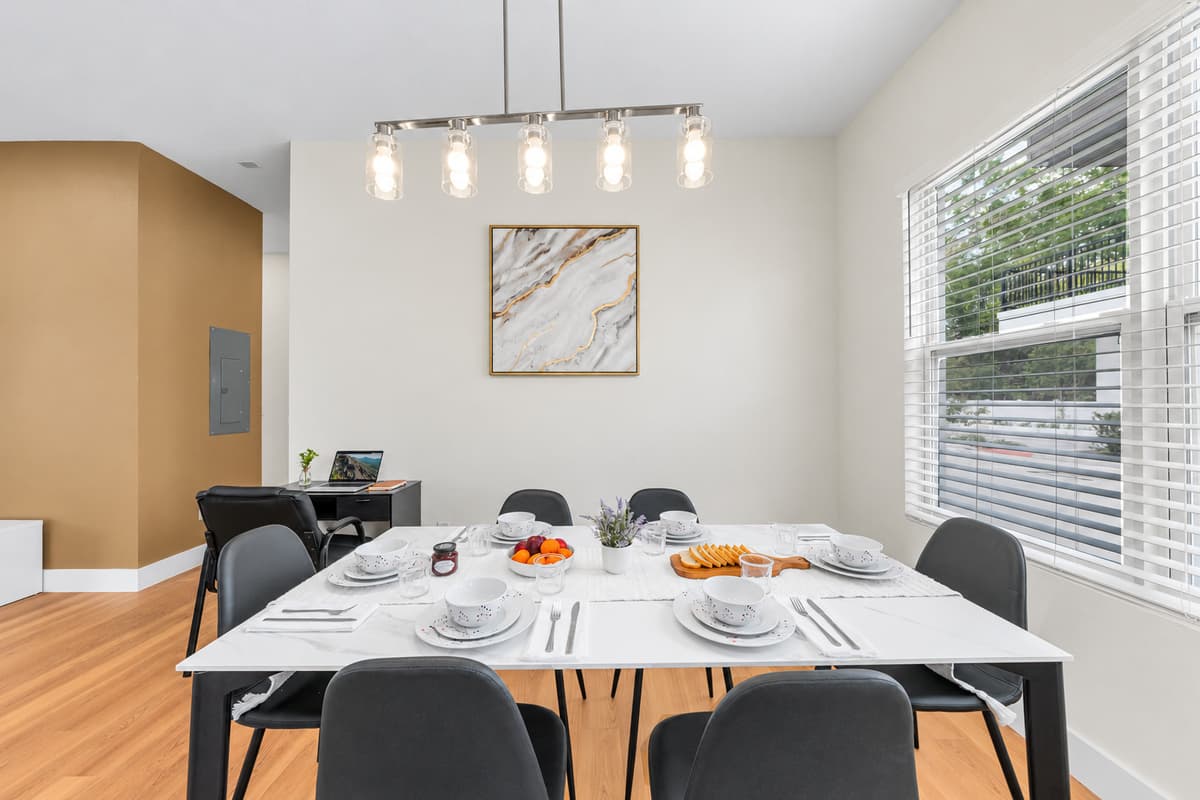 Gather around the dining table, set for a home-cooked meal under stylish pendant lighting.