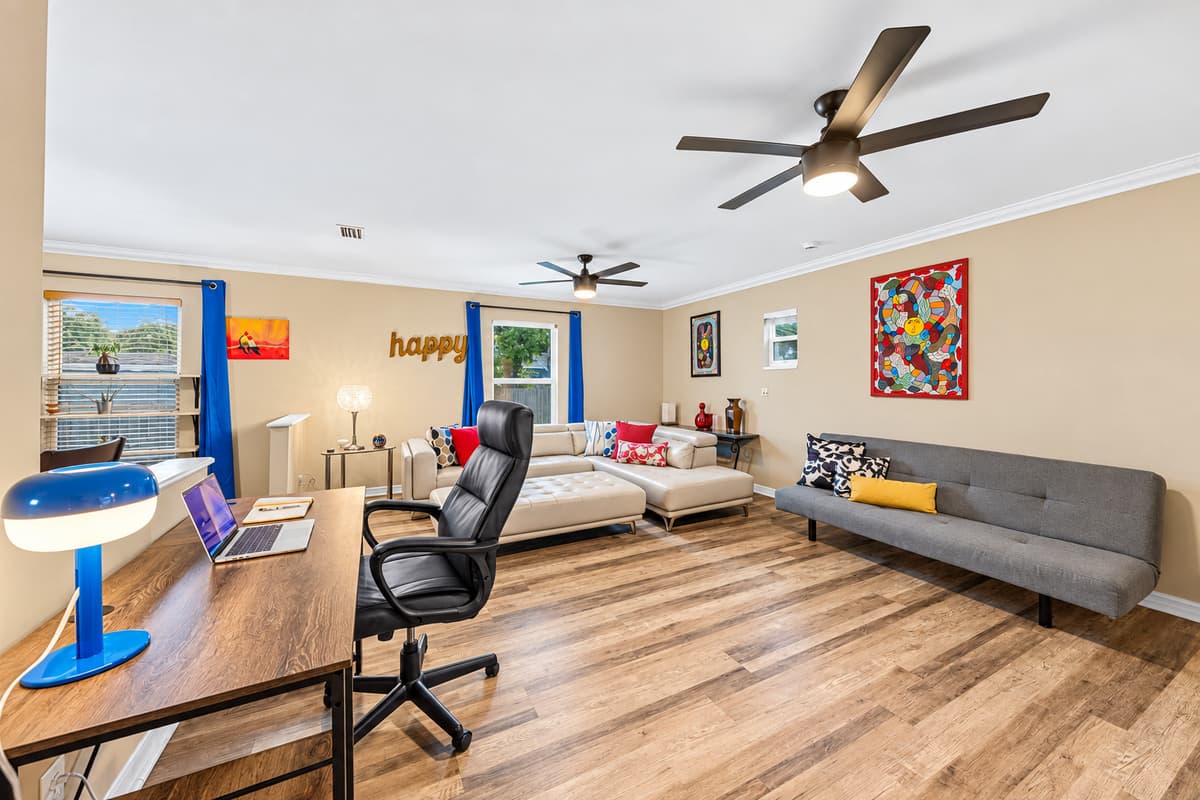 Spacious lounge with workspace setup, large sectional, and bright windows—perfect for both work and relaxation.