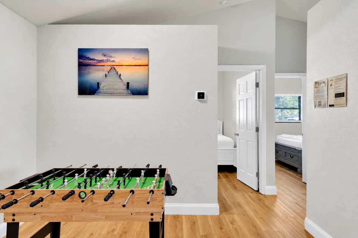 Foosball on one side, bedrooms and bathroom a few steps away — so the tournament never has to stop for anyone to go find something. Open floor, wood underfoot, and enough room around the table for a crowd to gather.