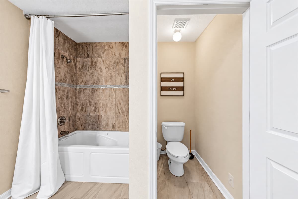 Clean and functional bathroom featuring a tub/shower combo and private toilet area.