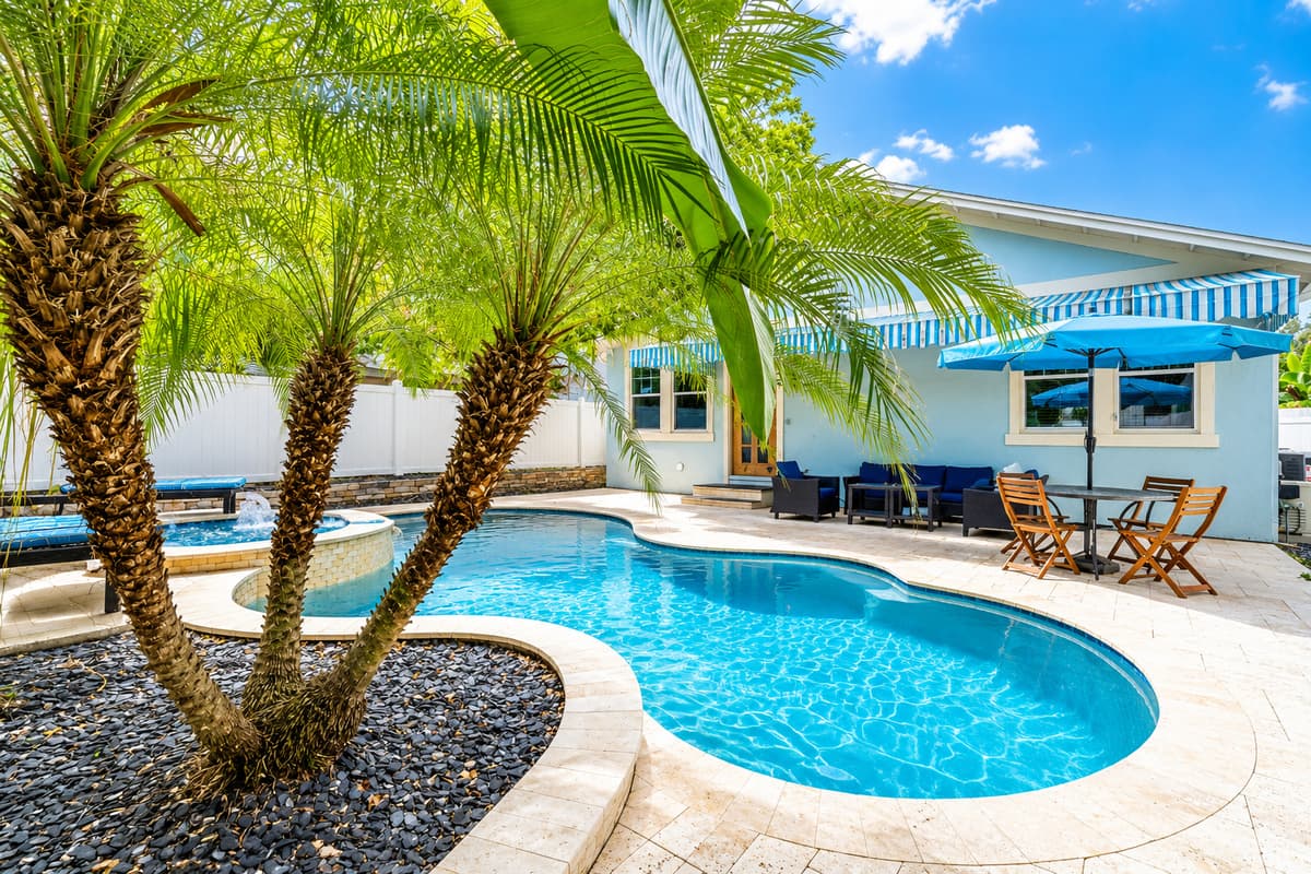 Relax in your own tropical backyard oasis featuring a sparkling private pool, attached spa, shaded patio, and lush palm trees—perfect for soaking up the Florida sunshine.