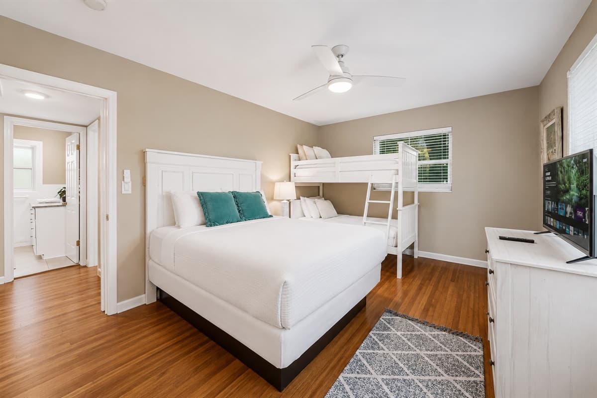 Family-friendly bedroom featuring a queen bed, twin bunk beds, and a bright open layout.