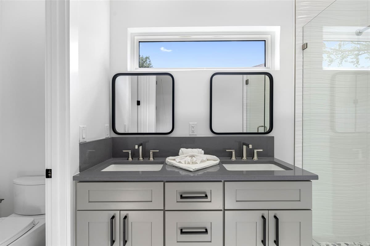 This full bathroom offers a sleek and modern double sink vanity, perfect for accommodating multiple guests at once.