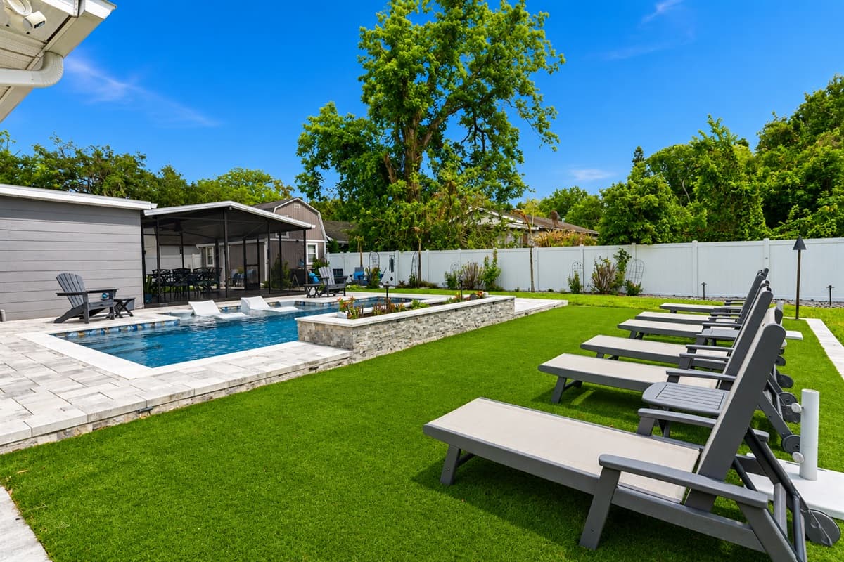 Spacious backyard retreat with luxury lounge seating, manicured lawn, and private pool views.