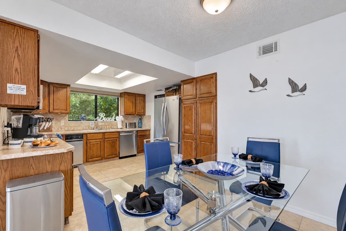 The dining area features a sleek and modern glass table that comfortably accommodates up to four people.