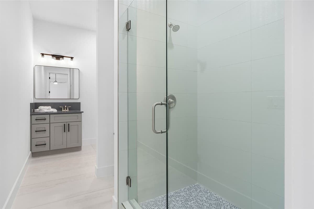 The spacious walk-in shower, framed by elegant glass doors, enhances the room's contemporary design.