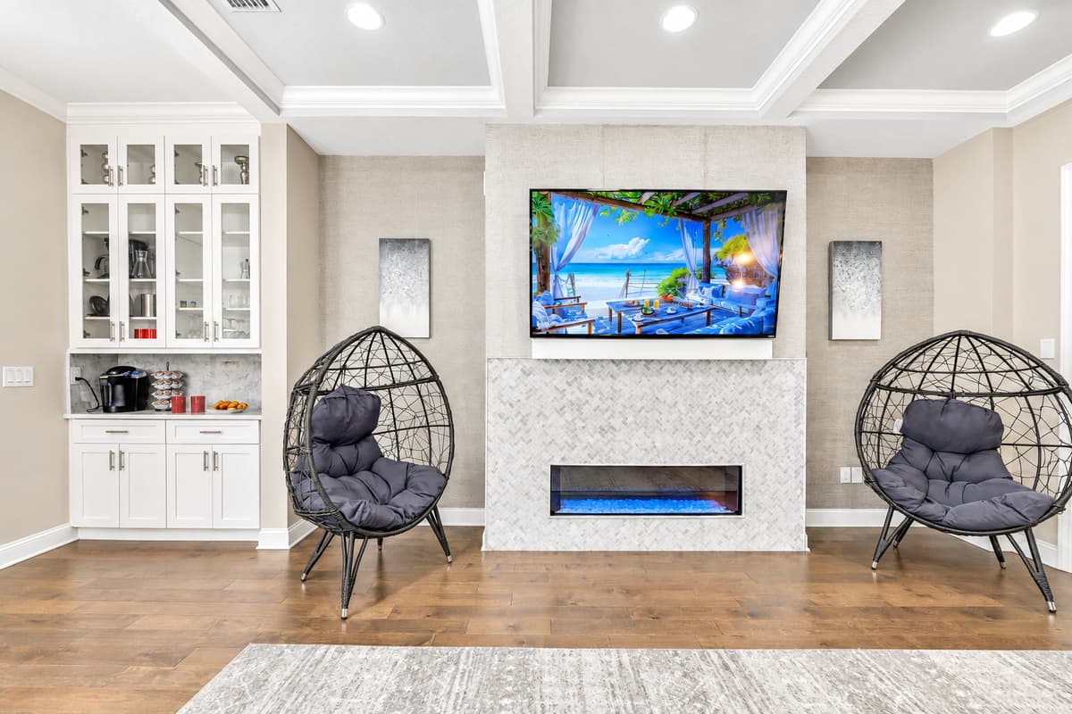 The room's warm wooden floors add a touch of rustic charm, enhancing the cozy atmosphere and providing a beautiful contrast to the plush furnishings.