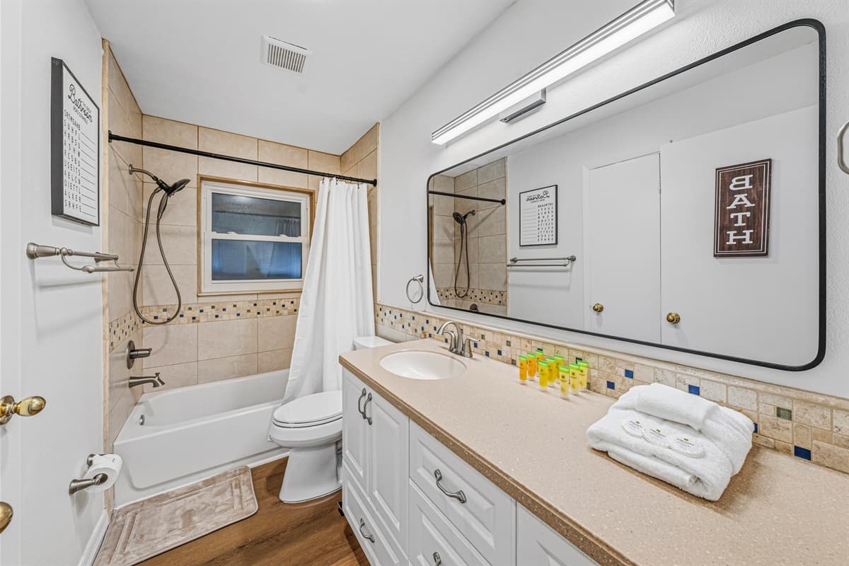 Full bathroom featuring a combination tub/shower, spacious vanity, and essential amenities 