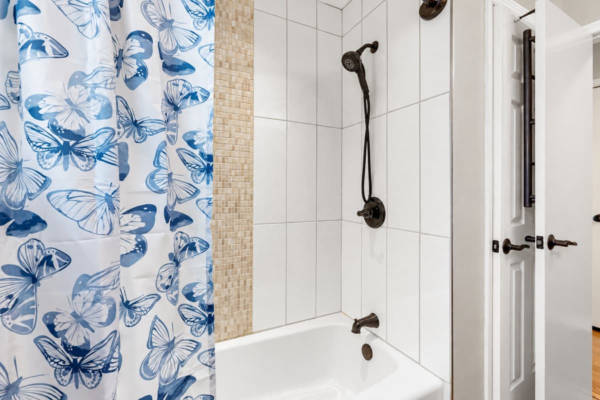 Designed for comfort and convenience, this full bathroom features a classic tub and shower setup with kid-friendly touches and a lighthearted butterfly curtain that appeals to guests of all ages.