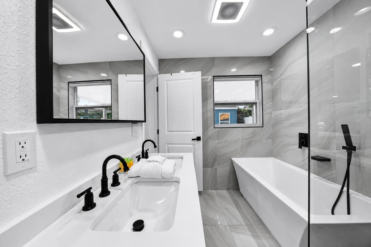 Luxurious en-suite bathroom (Master bedroom) featuring a double vanity, oversized mirror, soaking tub, and glass-enclosed walk-in shower.