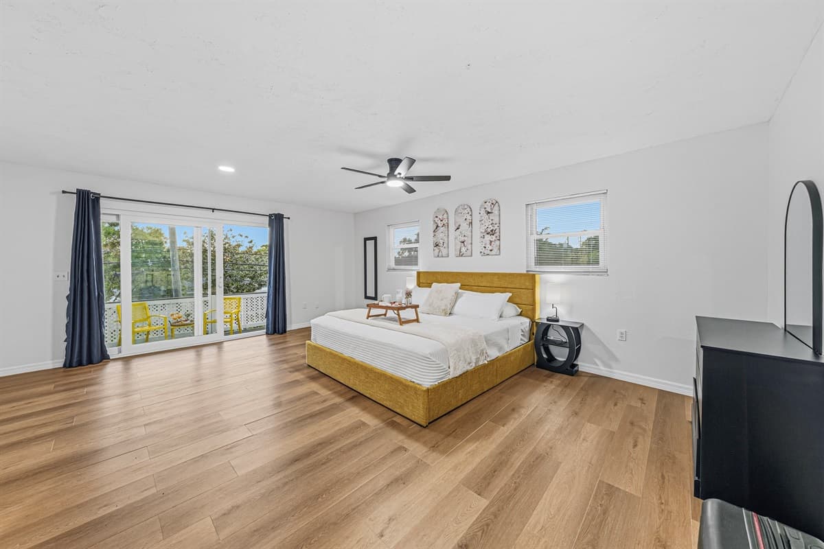 Bright and airy bedroom with king bed and sliding glass doors leading to outdoor seating 