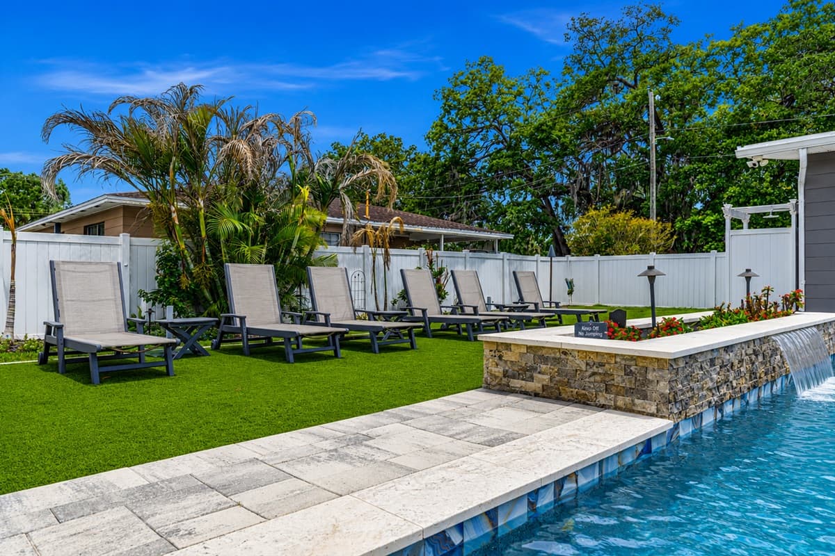 Beautiful resort-style pool area featuring luxurious loungers, lush landscaping, and plenty of space to relax under the Florida sun.
