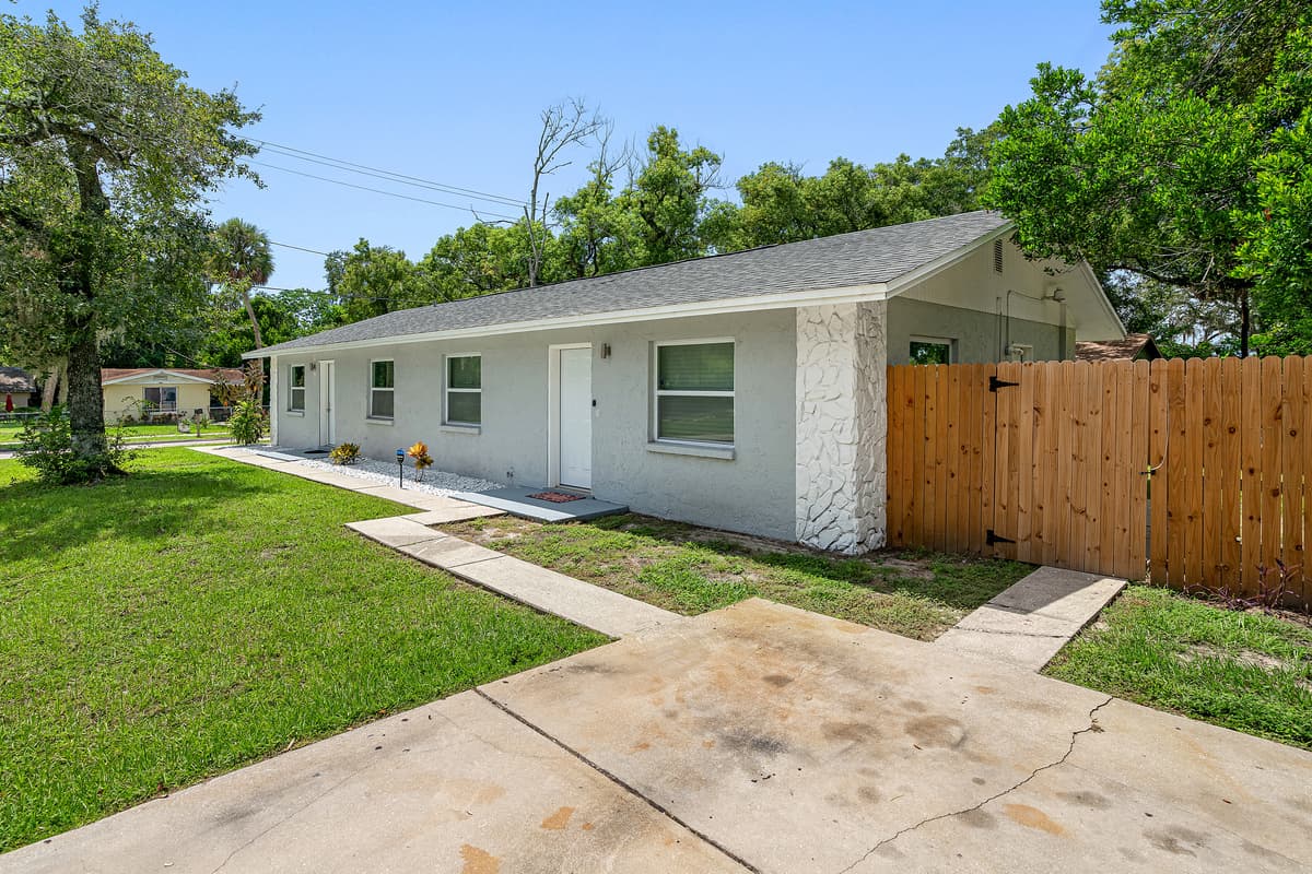 The lovely back view of this amazing property showcasing the backyard fence, the spacious driveway, and the walk path to the entance of the property. Book now!