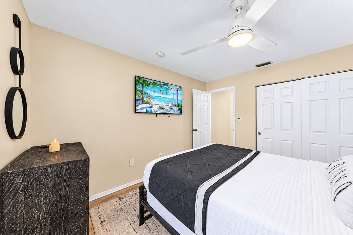 Spacious guest bedroom featuring a queen bed, Smart TV, and ample storage.