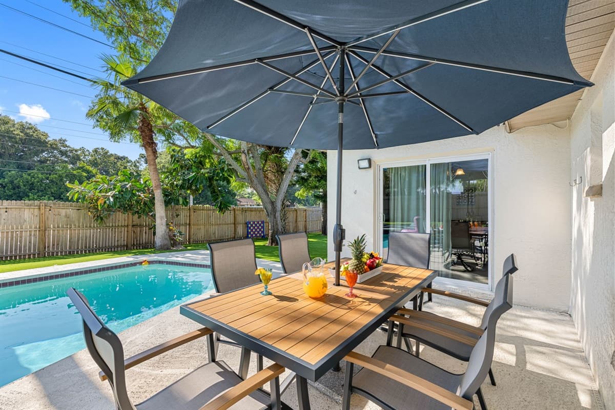 The dining area, perfectly positioned near the shimmering pool, offers an ideal setting for family meals or gatherings with friends.