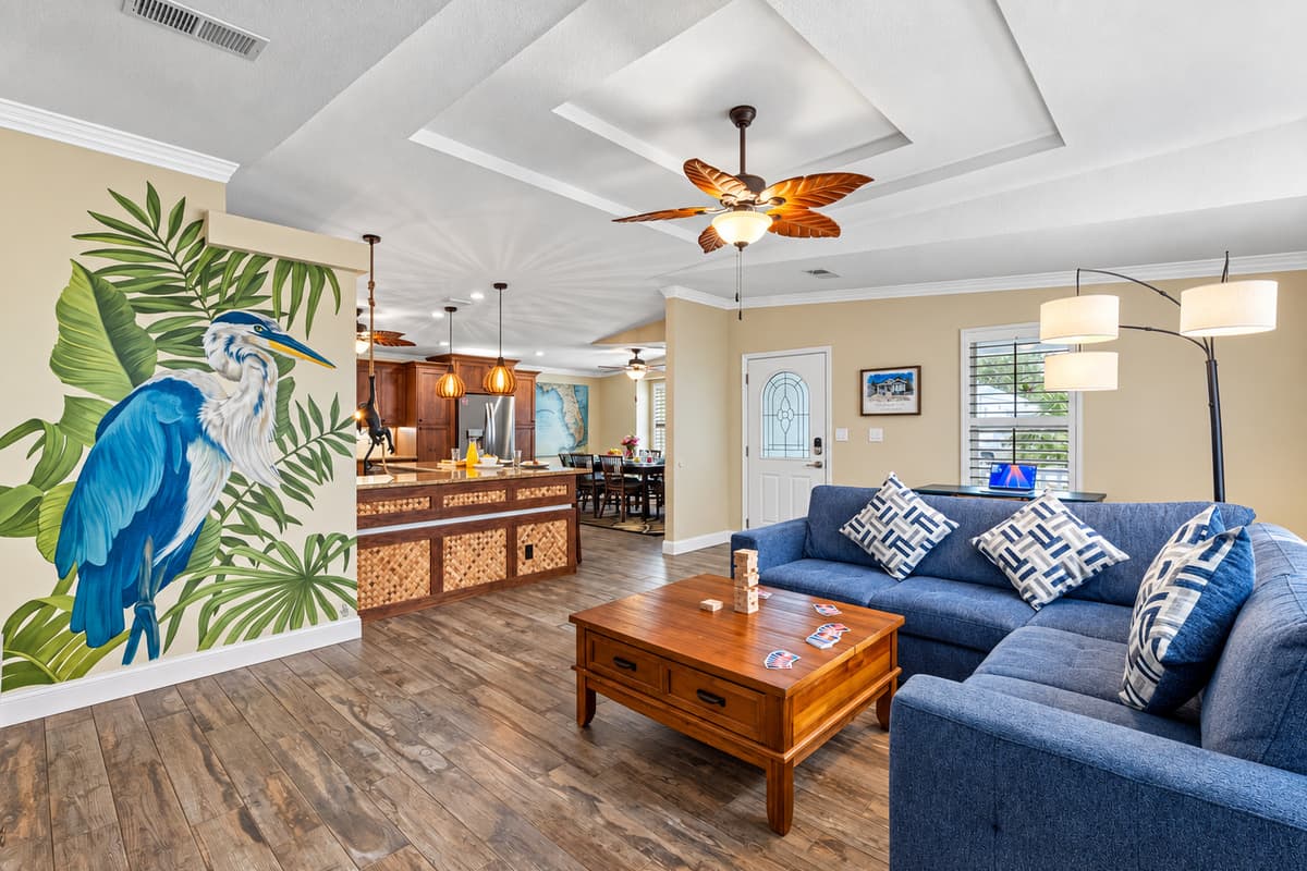 Experience Florida living at its finest in this stylish living space, complete with a large smart TV, spacious sectional, and beautiful tropical artwork.