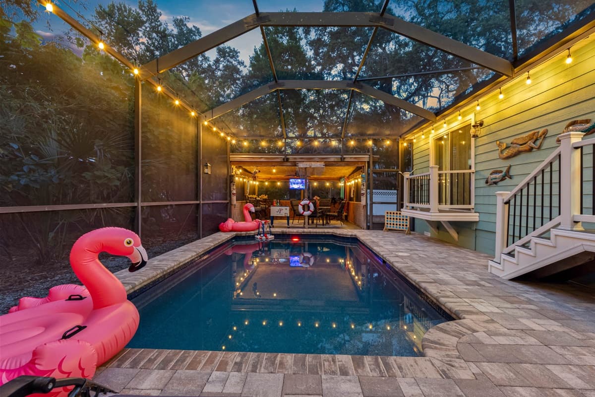 This inviting pool space offers both relaxation and entertainment, complete with lounge chairs, floats, and a cozy adjacent patio bar.