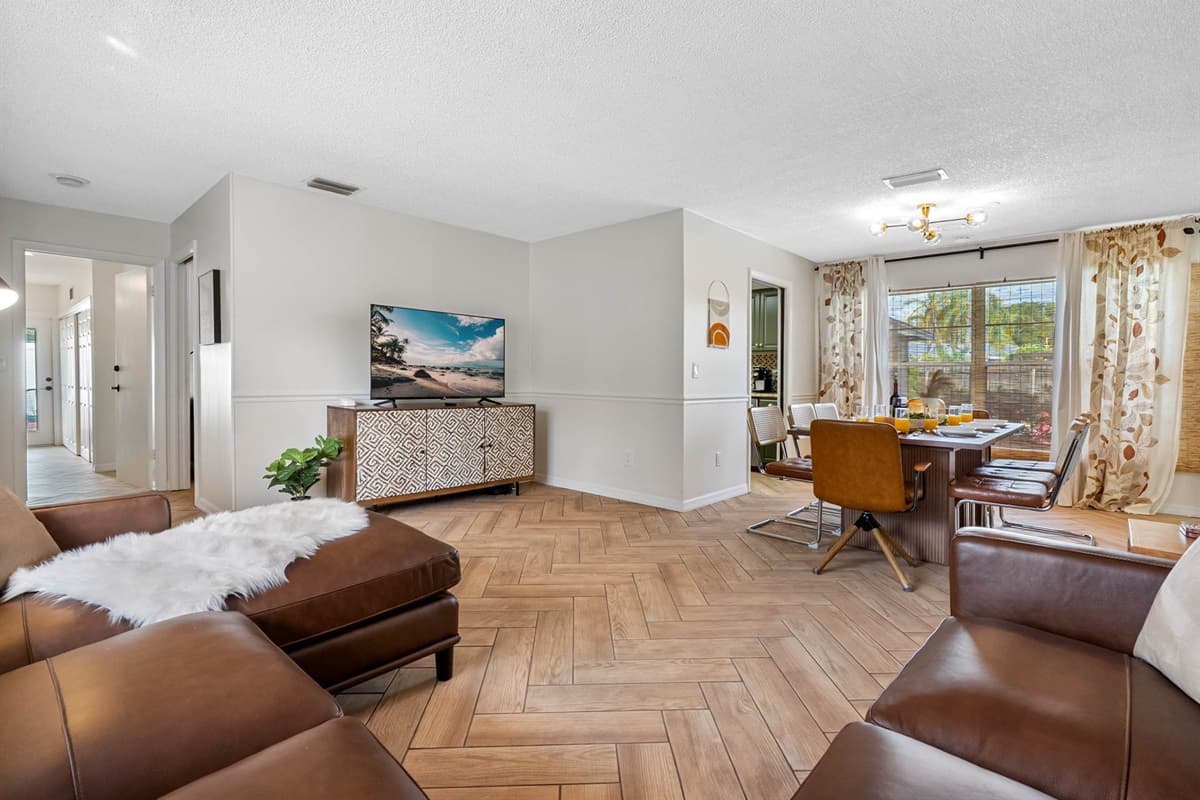 Enjoy the warmth of this thoughtfully styled living space featuring earth-tone decor, light wood flooring, and a comfortable sectional sofa for group lounging or solo downtime.