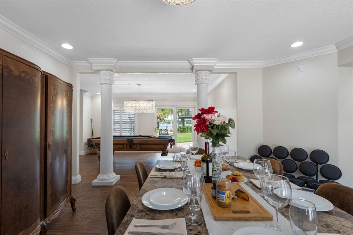 A blend of traditional elements—like decorative columns and antique-style cabinet—with modern finishes creates a versatile dining room style.