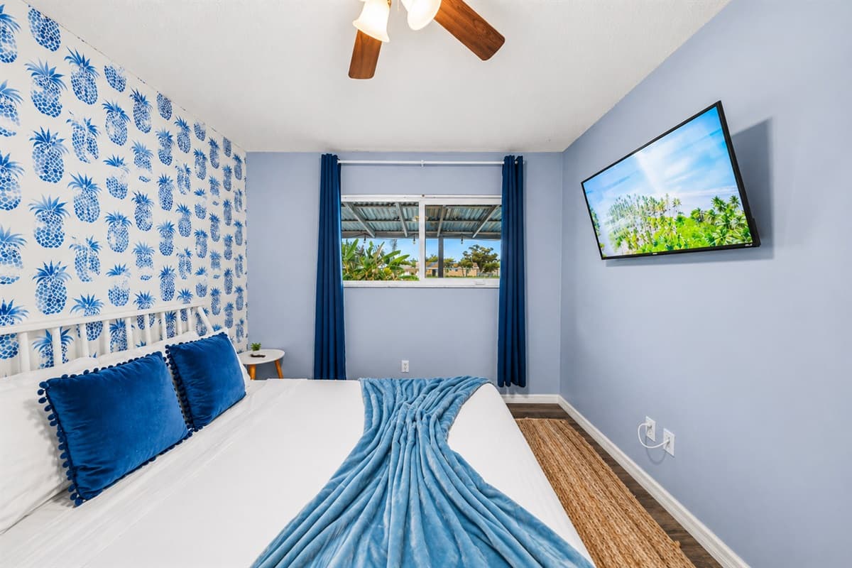 Relaxing retreat with wall-mounted TV, soft blue tones, and a cozy, beach-inspired atmosphere.