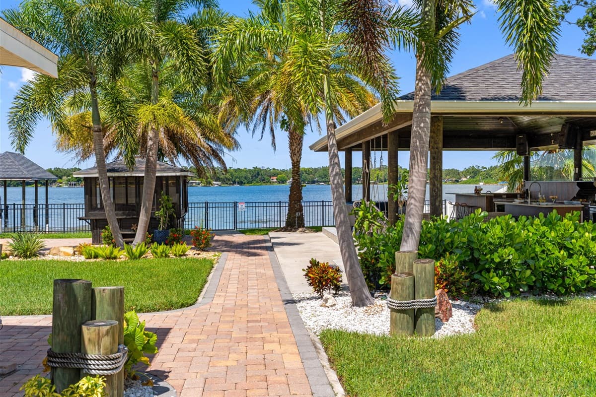 Blend indoor comfort with outdoor charm in this covered kitchen and seating area, set against a backdrop of sparkling water views.