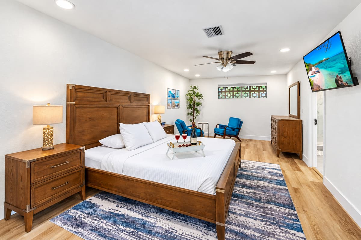 Relax in this airy, light-filled bedroom with upscale furniture, a mounted flat-screen TV, and a private sitting area ideal for wine or winding down.