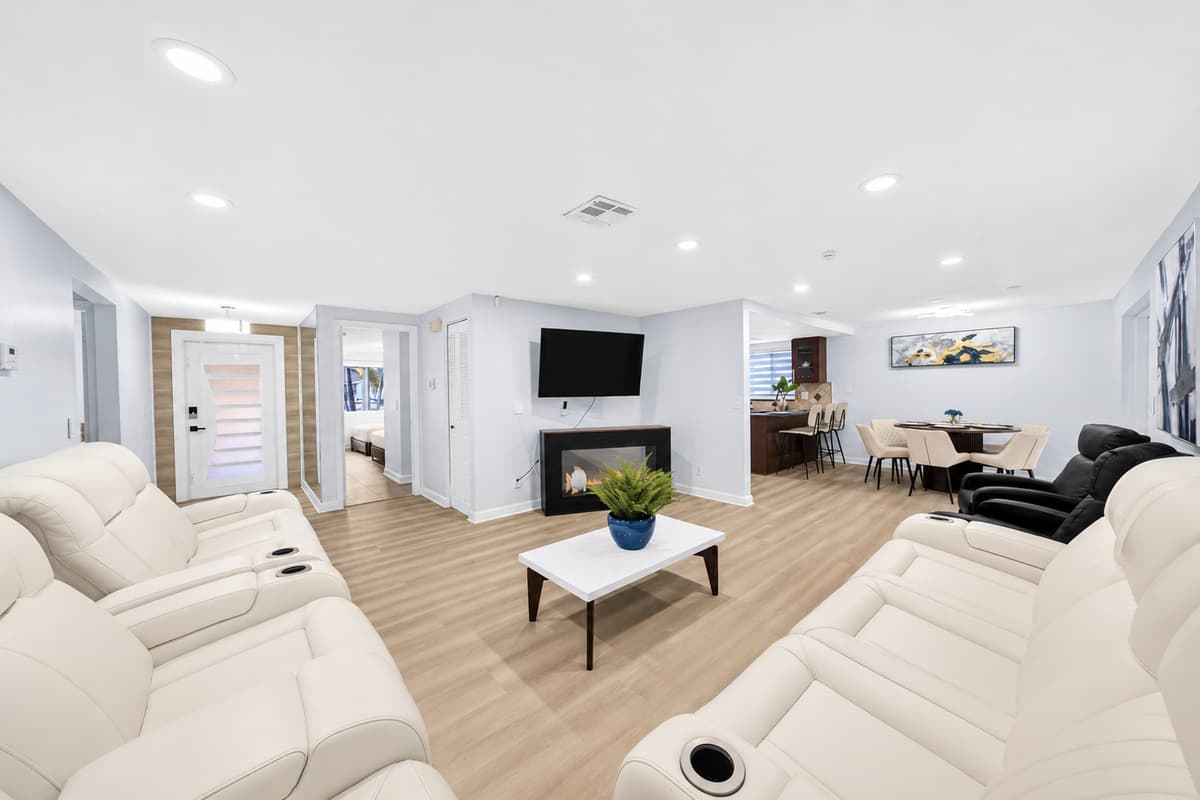 Spacious open-concept living room featuring comfortable reclining sofas, a large TV, and plenty of seating for family gatherings and movie nights.