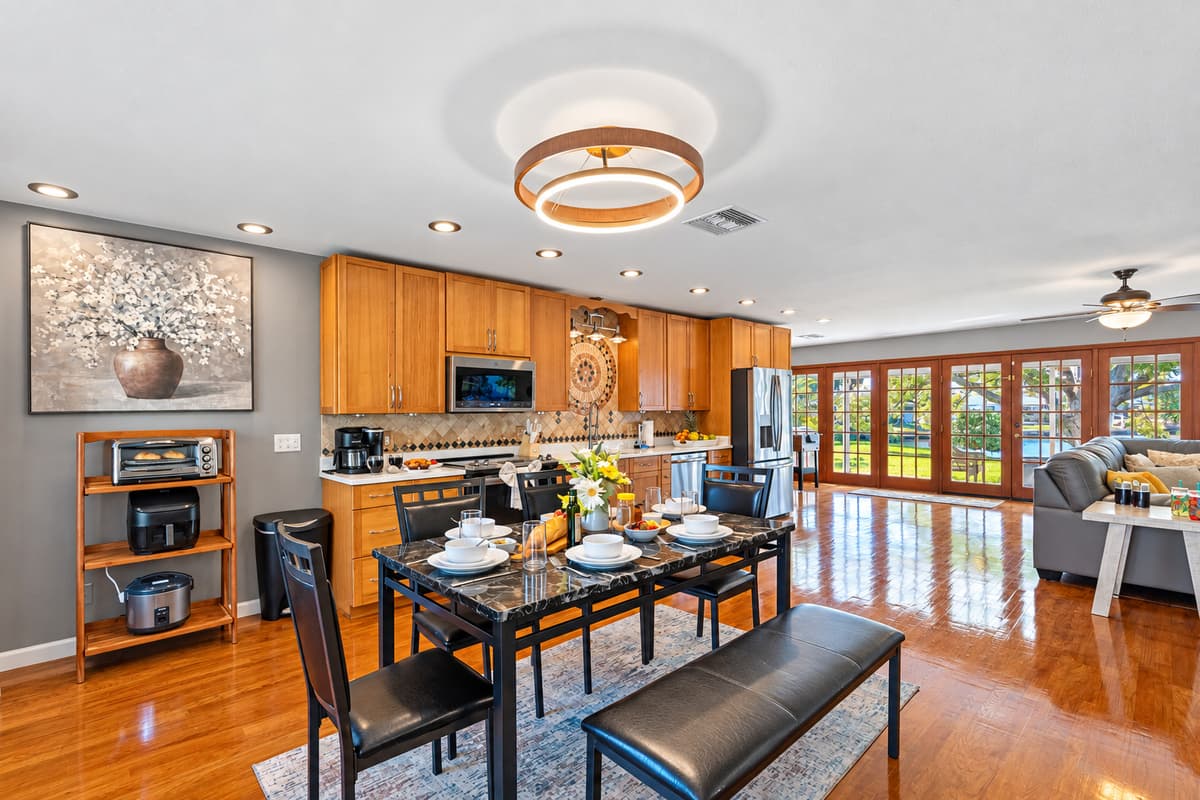With a sleek black dining table, modern lighting, and a fresh floral centerpiece, the space balances elegance with casual charm.