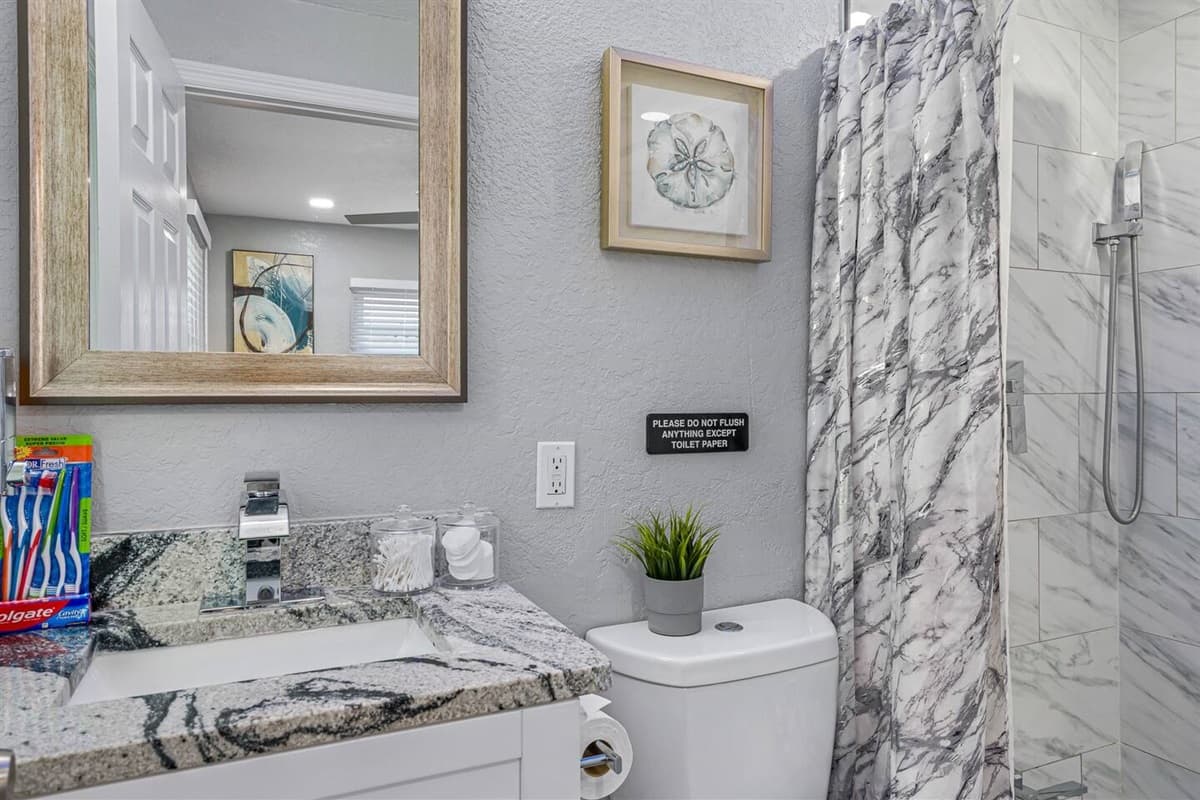 This bathroom has a sink, toilet, shower, and wide vanity mirror.