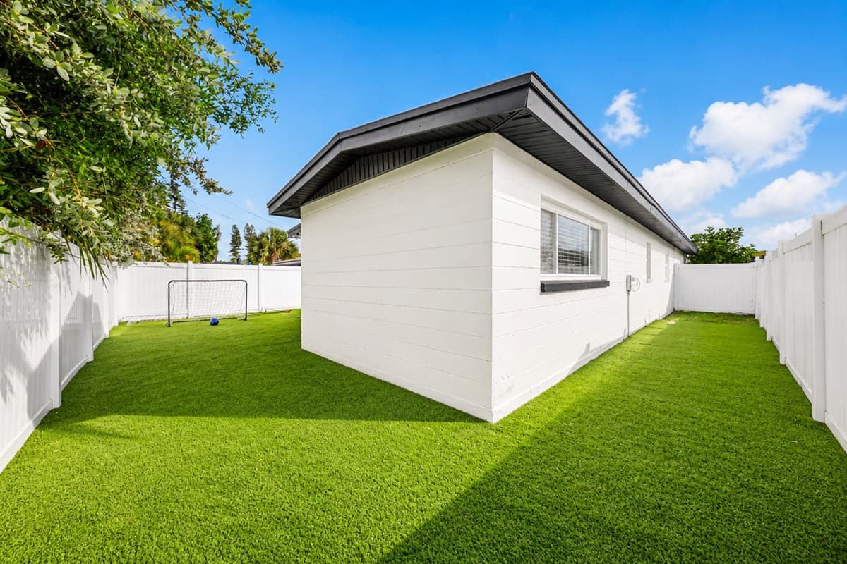 Side yard view highlighting the spacious fenced lawn and private outdoor setting.