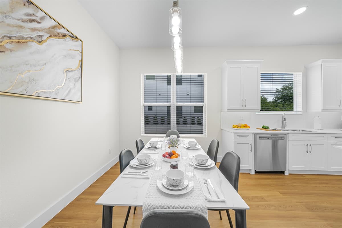 Bright and elegant dining area with seating for guests, set beside a modern kitchen—perfect for shared meals and gatherings.