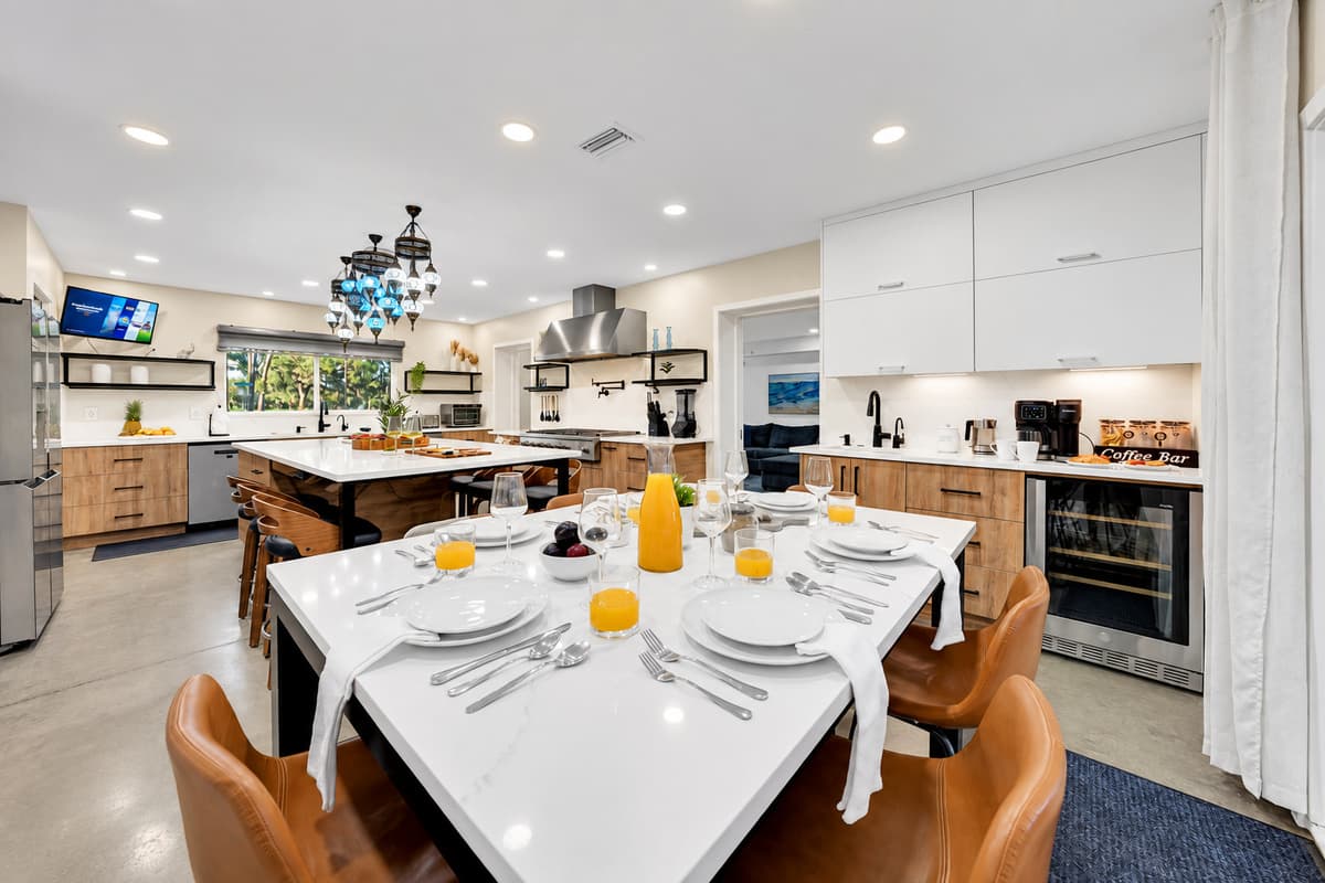 Breakfast for sixteen, all at once. Full place settings along the island under statement lighting, with the range and ovens steps away. Nobody eats in shifts here.