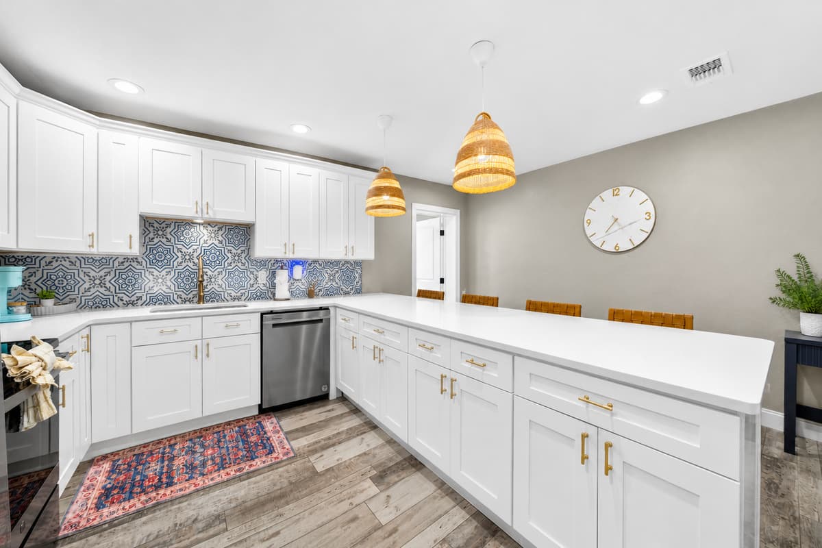 Bright, modern kitchen featuring white shaker cabinets, a large center island, stainless steel appliances, and stylish patterned tile backsplash.