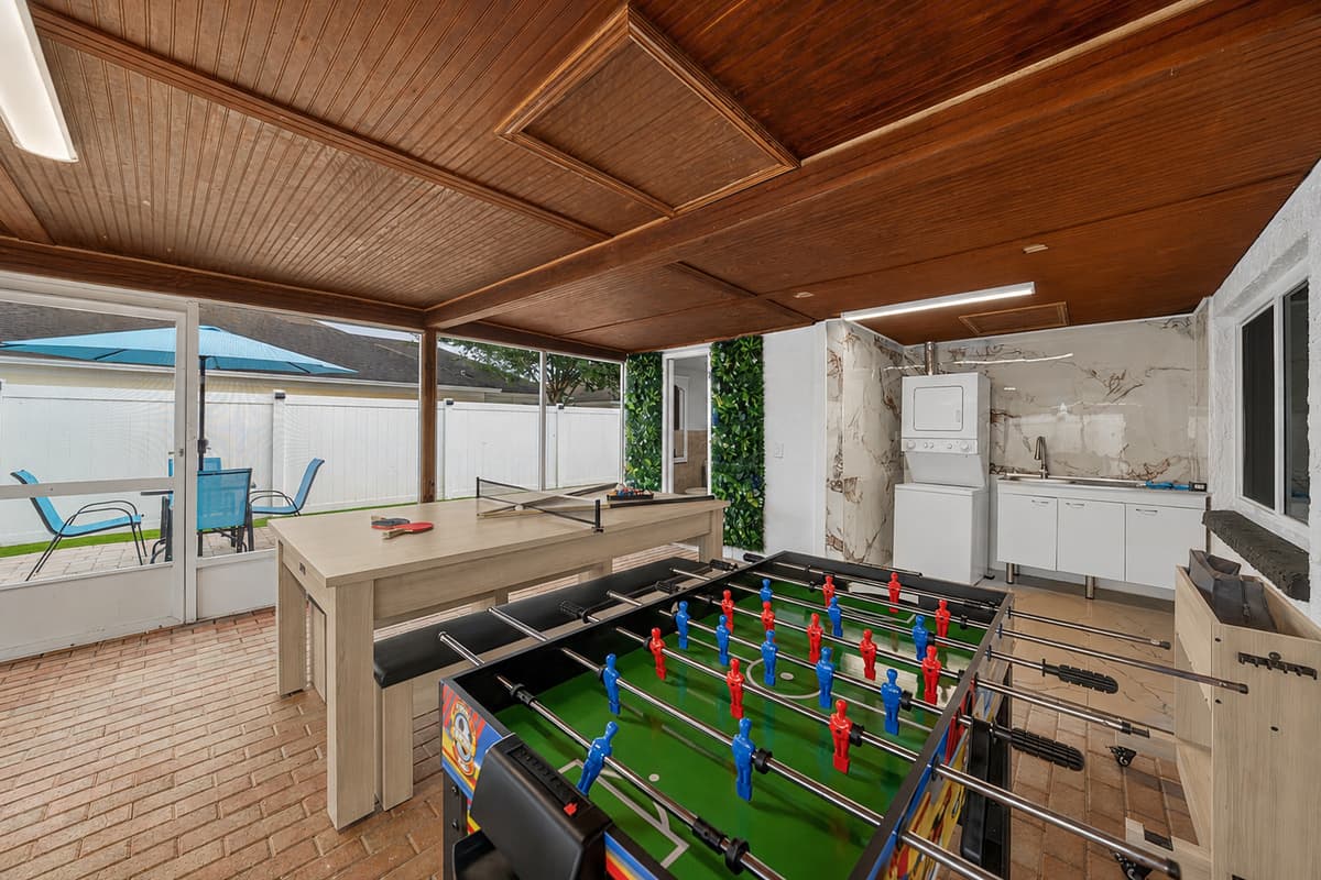 Game-filled patio featuring foosball, pool table fun, and a spacious covered setting perfect for family competitions and group gatherings.
