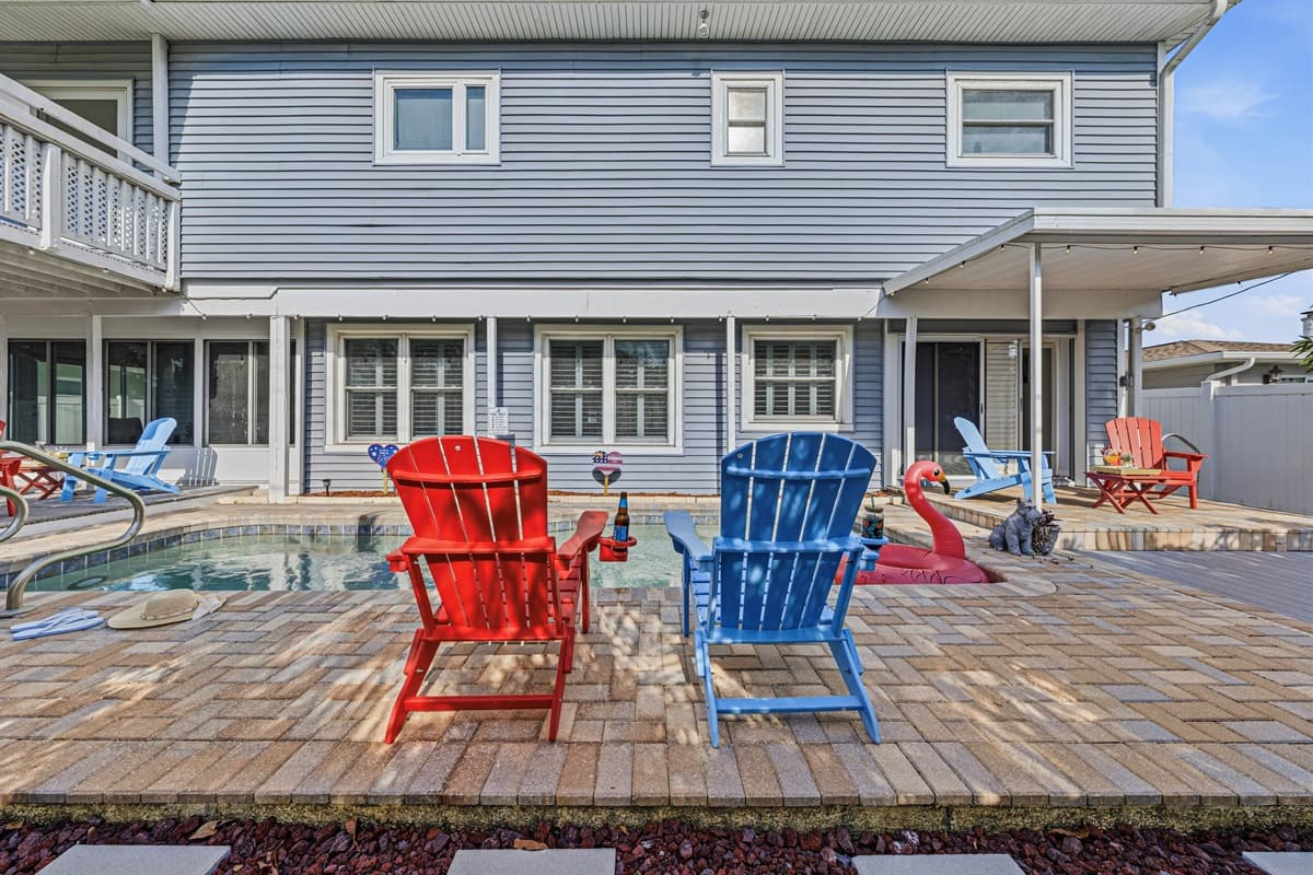 Wide view of the backyard oasis featuring pool, seating, and plenty of space for everyone to enjoy 