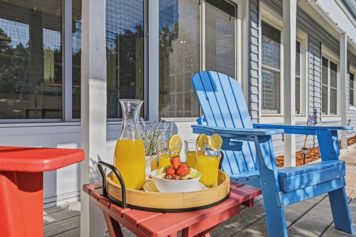 Outdoor seating area with colorful Adirondack chairs and a cozy setup—perfect for relaxing poolside 
Food and drinks shown are for staging purposes only and are not included.