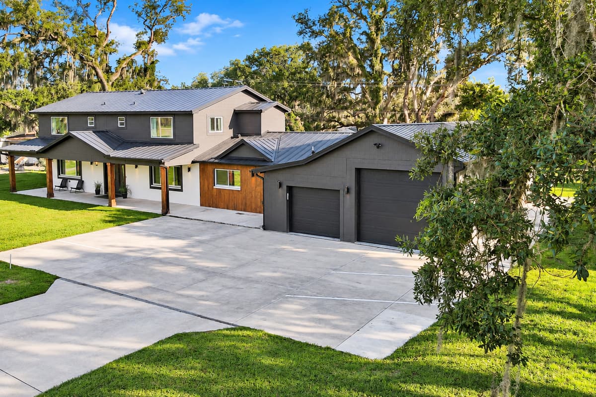 Bring every car. There is room for all of them. A driveway wide enough for six vehicles, two garage bays and a lawn that runs to the trees. Arrive as a convoy, park in one pass, and nobody moves a single car all week.