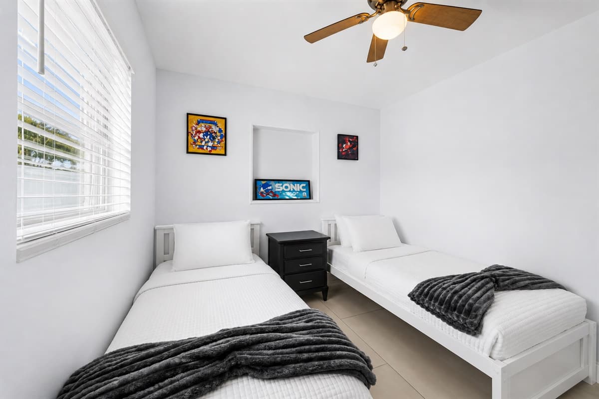 Bright guest room with two twin beds, stylish bedding, and sunny window views.