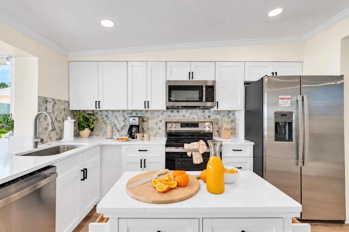 A bright kitchen ready for real meals. Stainless appliances, white cabinets, quartz counters and a prep island. Fresh orange juice in the morning, family dinners at night.